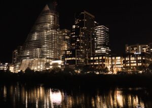 Illuminated skyscrapers reflecting in the river at night in downtown Austin, Texas.