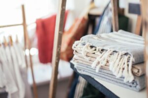Soft towels with tassels on shelf on blurred background of many clothes hanging on clothesline